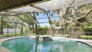 Piscina coberta com hidromassagem, cercada por árvores e um muro branco.