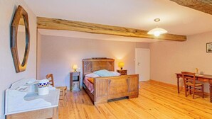 Een slaapkamer met een houten bed, nachtkastjes, een bureau en een stoel.