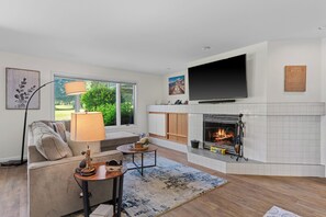 A modern living room with a fireplace, a flat-screen TV, a sofa, and a coffee table. - Arrowleaf | Golf & Pond Views | Ground-Floor Kahler Glen Condo | Sleeps 4 (Leavenworth)