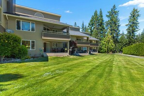 A multi-story residential building with a well-maintained lawn, large windows, and a balcony. - Arrowleaf | Golf & Pond Views | Ground-Floor Kahler Glen Condo | Sleeps 4 (Leavenworth)