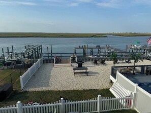Een terras aan het water met een barbecue, zitplaatsen en uitzicht op het water.