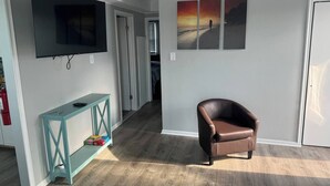 Un saló amb televisió, una taula de consola, un butac armchair de pell i un quadre a la paret.