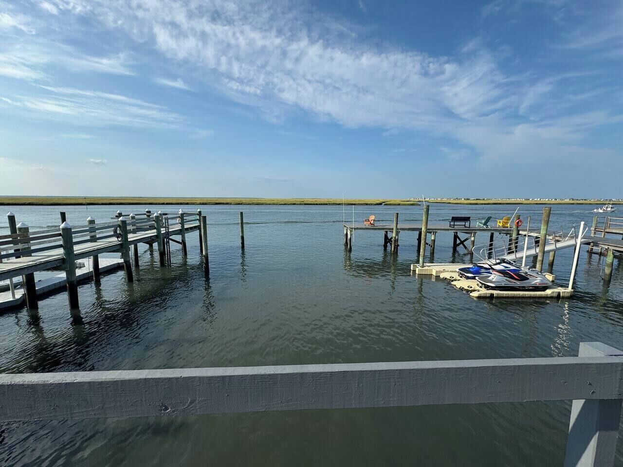 Ruhiges Ufer mit einer Anlegestelle, einem kleinen Boot und einer Pier, die ins Wasser ragt.