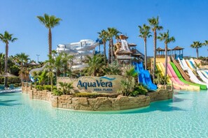 A water park with multiple slides, a pool, and palm trees.
