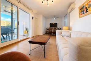 Ein Wohnzimmer mit einer Couch, einem Couchtisch, einem Fernseher und einem Essbereich mit Stühlen und einem Tisch.