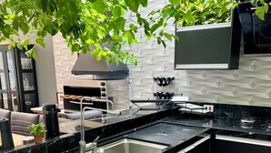 A modern kitchen with black cabinetry, a stainless steel sink, and a gas stove. - Mansion in Curitiba with jacuzzi and heated pool inside the house, sleeps up to 10 people. (Curitiba)