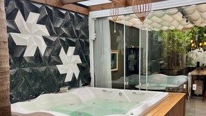 A hot tub in a covered outdoor area with wooden steps and a geometric wall design. - Mansion in Curitiba with jacuzzi and heated pool inside the house, sleeps up to 10 people. (Curitiba)