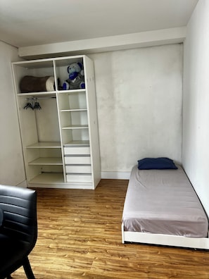 A bedroom with a bed, a wardrobe, and a chair.