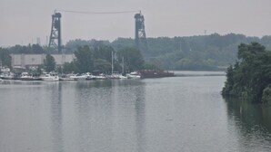 A river with boats docked, a bridge in the background, and trees along the riverbank. - Lake Erie Fishing - Sleeps 8 · 3 Bd - 1.5 Bth - Full Kitchen - Patio - Out Elec. (Lorain)