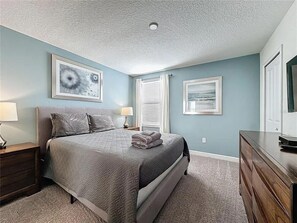Une chambre à coucher comprenant un lit, des tables de chevet, une commode et des œuvres d’art accrochées aux murs.