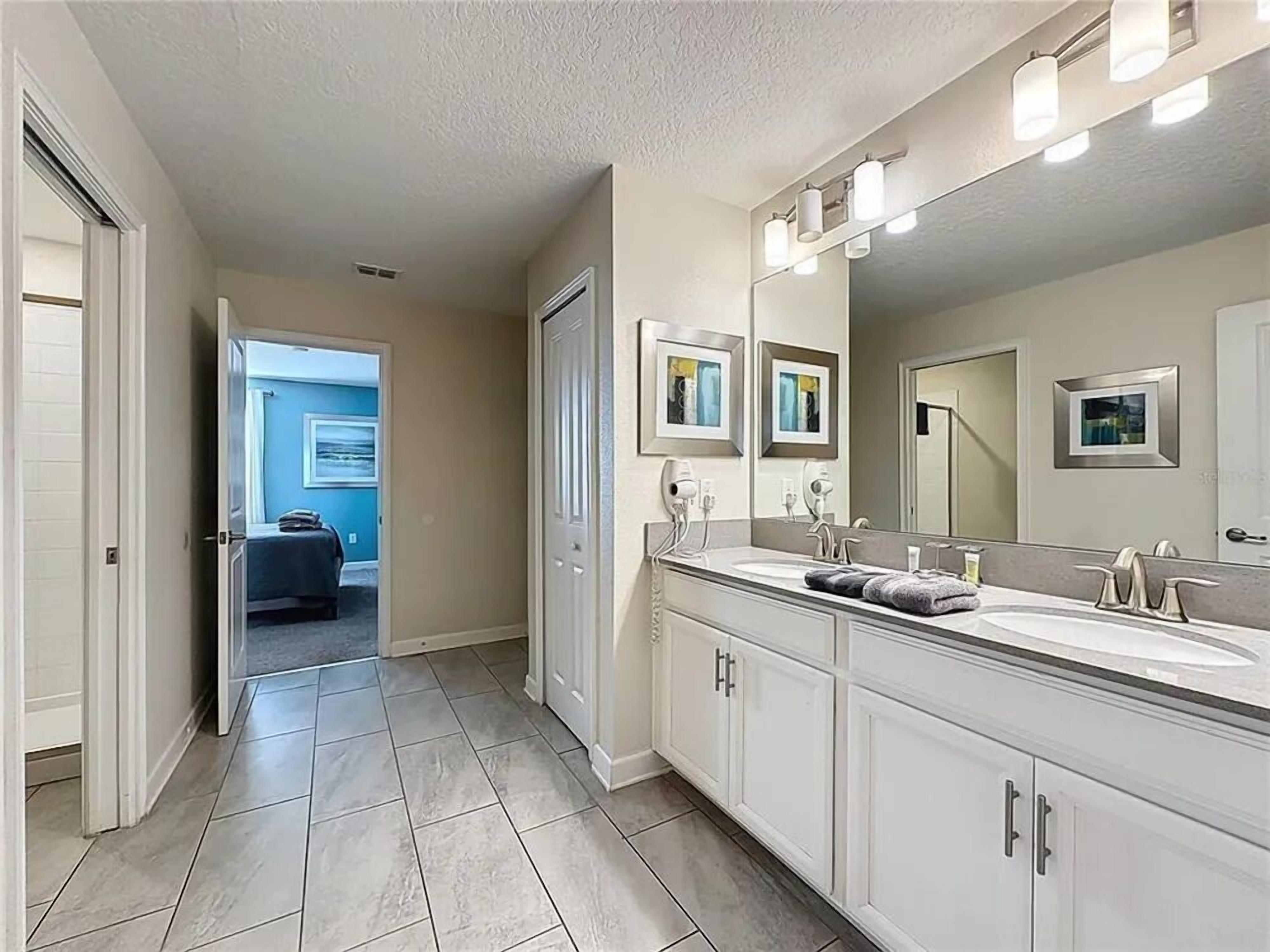 A bathroom with a double sink, large mirror, and light fixtures.