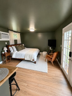 Ein Schlafzimmer mit Bett, Nachttischen, Schreibtisch, Stuhl, Fernseher und Fenster.