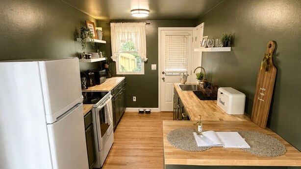 Eine kompakte Küche mit Kühlschrank, Backofen und Spüle, Holz Arbeitsplatten und einer kleinen Kücheninsel mit Hockern.