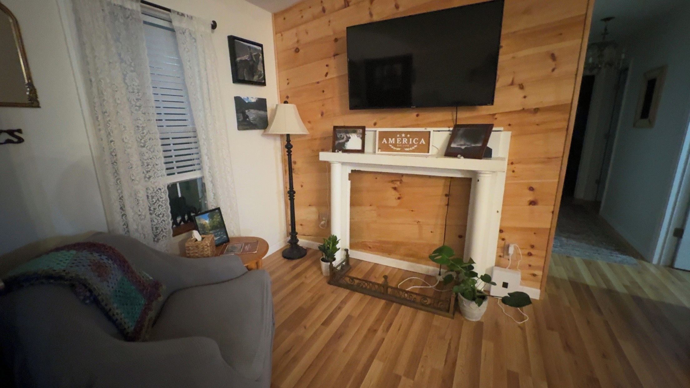 Een woonkamer met een open haard, een televisie erboven en een bank.