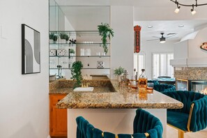 Una cocina moderna con encimeras de granito, una isla integrada y sillas tapizadas en color turquesa.
