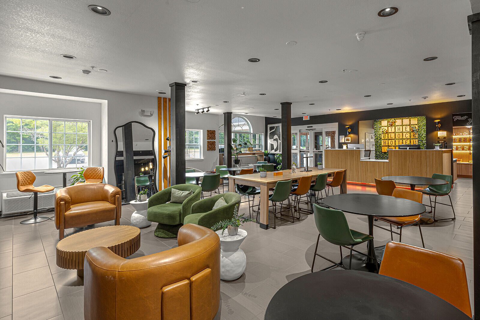 Um lobby de hotel moderno com uma receção, áreas de estar e vista para o exterior.