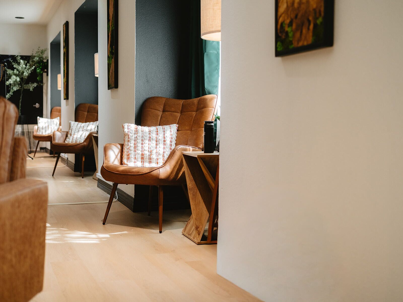 Um interior moderno com poltronas de couro, uma mesa de madeira e uma luminária na parede.