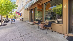 A sidewalk with outdoor seating, a storefront with large windows, and a building number 133. - Charming 1-bedroom Downtown Escape in Saugatuck, perfect for solo travelers. (Saugatuck)