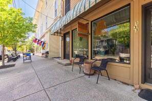 A sidewalk with outdoor seating, a storefront with large windows, and a building number 133. - Charming 1-bedroom Downtown Escape in Saugatuck, perfect for solo travelers. (Saugatuck)