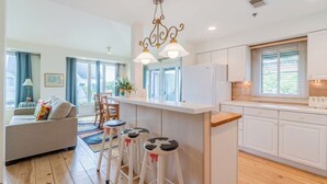 A modern kitchen with white cabinets, a central island with stools, and a chandelier. - Charming 1-bedroom Downtown Escape in Saugatuck, perfect for solo travelers. (Saugatuck)