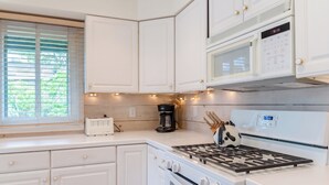 A kitchen with white cabinets, a stove, a microwave, and a coffee maker. - Charming 1-bedroom Downtown Escape in Saugatuck, perfect for solo travelers. (Saugatuck)