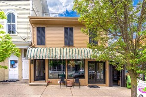 A two-story building with a storefront featuring a striped awning and large windows. - Charming 1-bedroom Downtown Escape in Saugatuck, perfect for solo travelers. (Saugatuck)