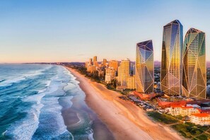 Un paysage urbain côtier avec des immeubles modernes de grande hauteur, une plage et un ciel dégagé.
