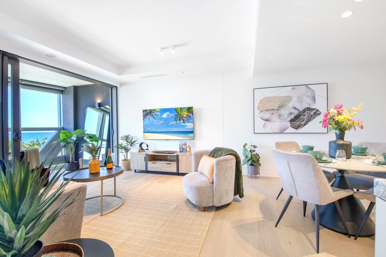 Uma sala de estar moderna com uma televisão grande, assentos confortáveis e uma área de jantar com louças verdes.