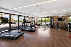 A modern gym with treadmills, stationary bikes, and weight machines. - Champagne Oceanview Suite- The Langham- wParking (Surfers Paradise)