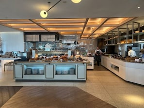 A modern kitchen with a central island, stainless steel appliances, and a high ceiling with recessed lighting. - Champagne Oceanview Suite- The Langham- wParking (Surfers Paradise)
