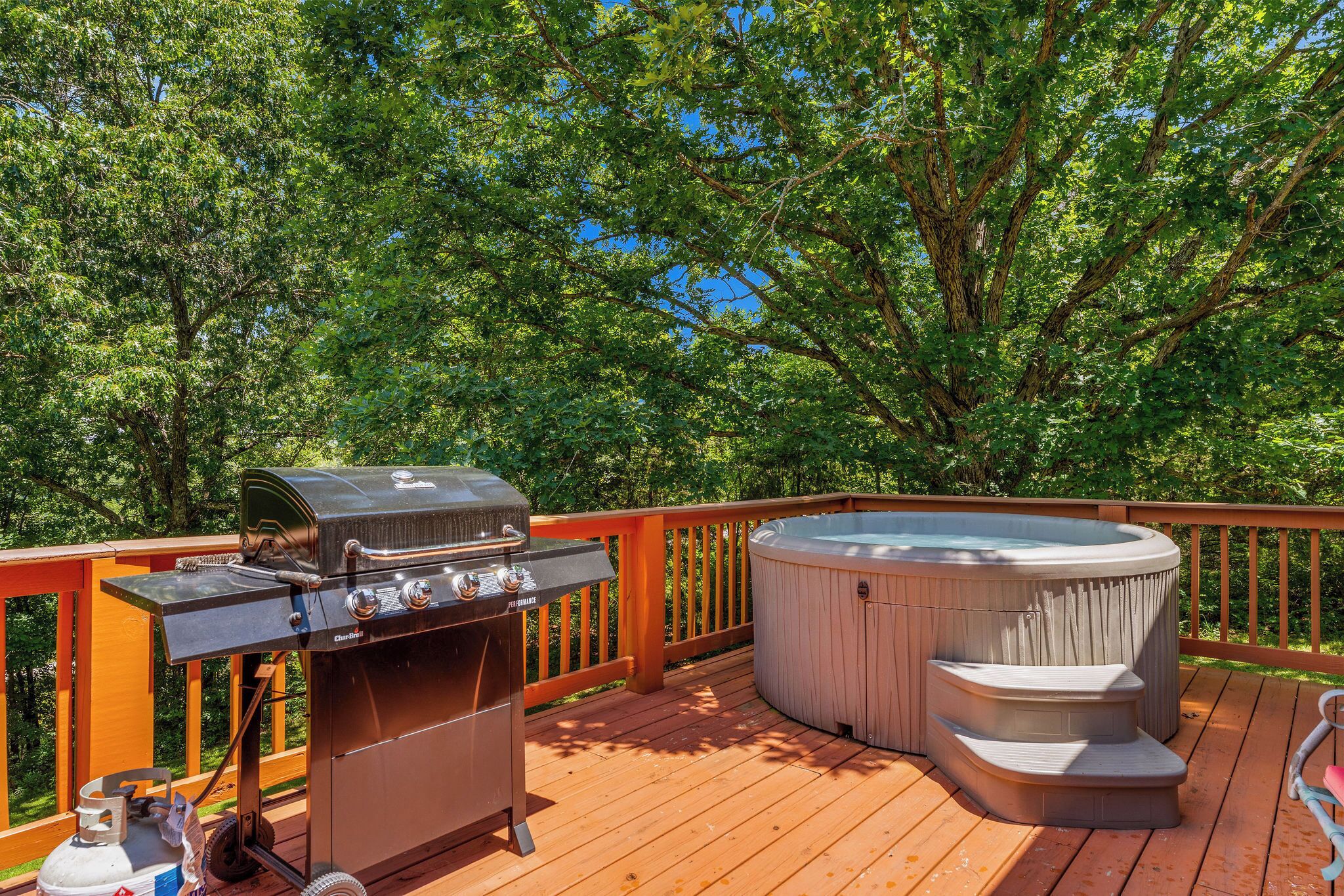 An outdoor deck with a barbecue grill and a hot tub.