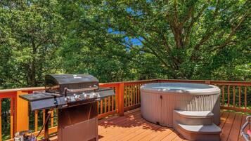 An outdoor deck with a barbecue grill and a hot tub.