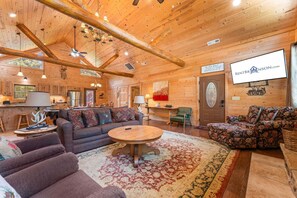 Ein Interieur einer Blockhütte mit einer Couch, einem runden Tisch und einem gemusterten Teppich.