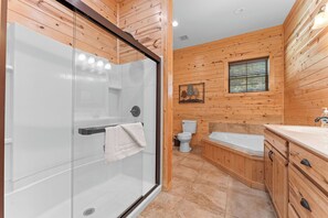 Un baño con ducha de vidrio, inodoro, bañera y paneles de madera.