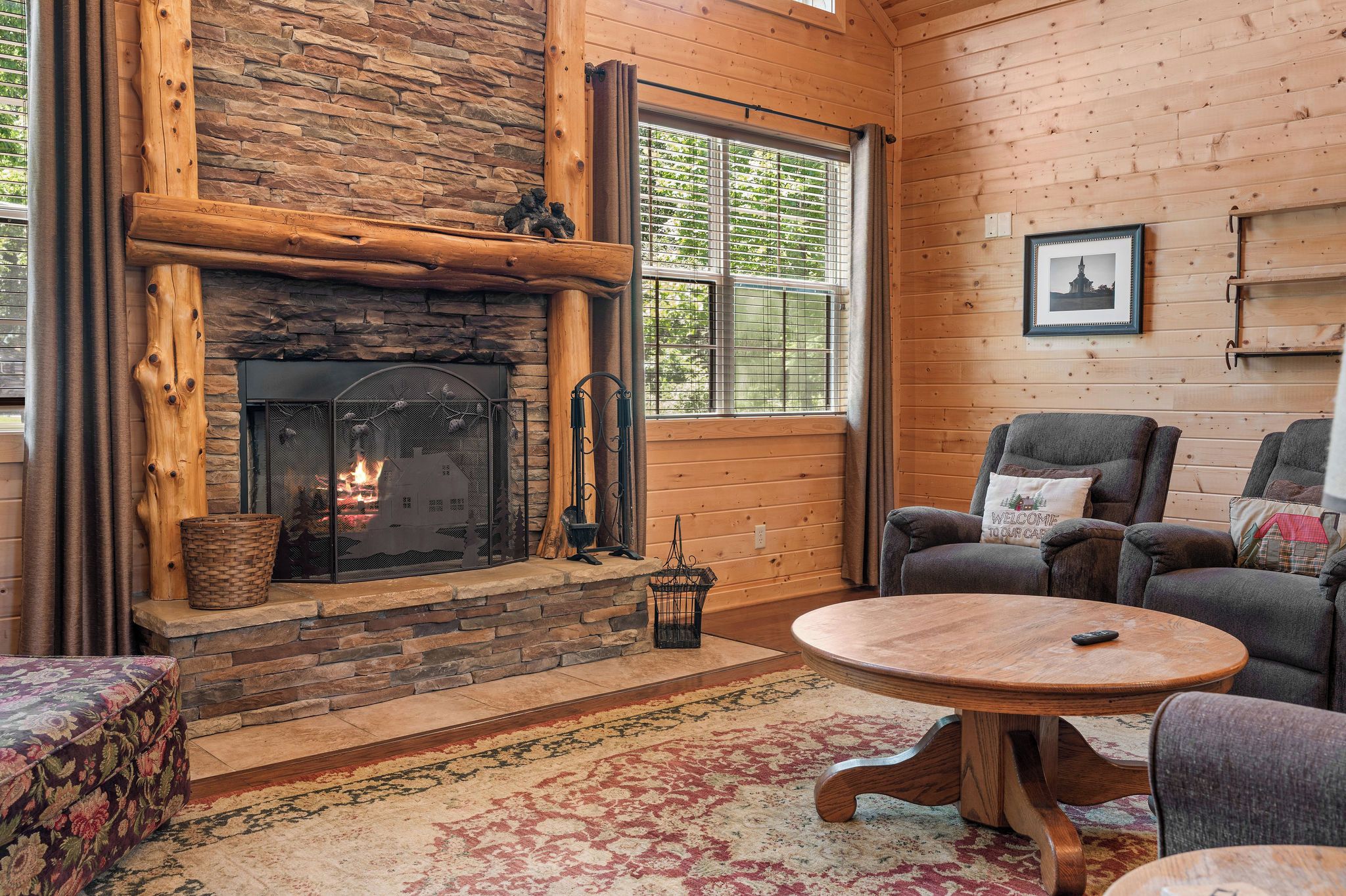 A cozy living room with a stone fireplace, a round wooden coffee table, and a comfortable seating area.