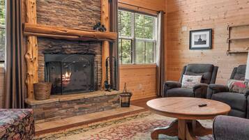 A cozy living room with a stone fireplace, a round wooden coffee table, and a comfortable seating area.