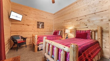A wooden cabin room with two beds, a television, and a chair.