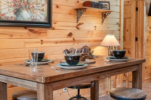 Ein Holztisch mit Schüsseln, einer Lampe und einem gerahmten Bild an der Wand.