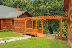 A wooden cabin with a covered porch and a stone pathway leading to it. - Secluded Ozark Log Cabin w/ Private Fire Pit, Hot Tub & Pool Table (Ridgedale)