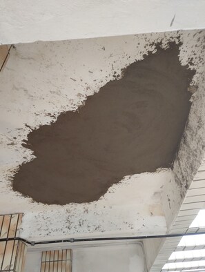 A ceiling with a large dark stain, a tiled floor, and a metal railing. - Pé na Areia Praia da Guilhermina VII (Praia Grande)