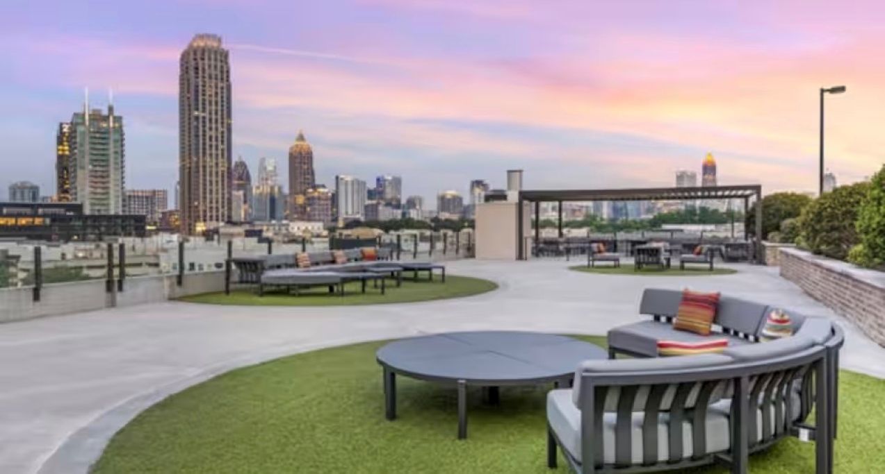 A rooftop terrace with seating areas, a city skyline view, and a covered section.