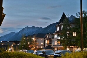 A mountain town with buildings, parked cars, and a mountain backdrop. - Our Home Your Holiday (Canmore)