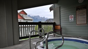 Un jacuzzi con barandillas metálicas, un cartel de no fumar y vistas a casas y montañas.