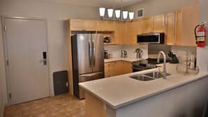 Una cocina moderna con electrodomésticos de acero inoxidable, armarios de madera, un horno empotrado y un lavaplatos de acero inoxidable.