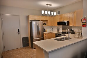 A modern kitchen with stainless steel appliances, wooden cabinets, a built-in oven, and a stainless steel sink. - Our Home Your Holiday (Canmore)
