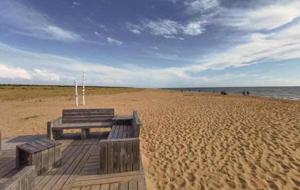 Ein Strand mit einer Holzterrasse und einem Dünenmarkierer.