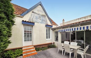 Ein Gebäude mit geneigtem Dach, einer Wandmalerei und einer Terrasse mit Außenplätzen.