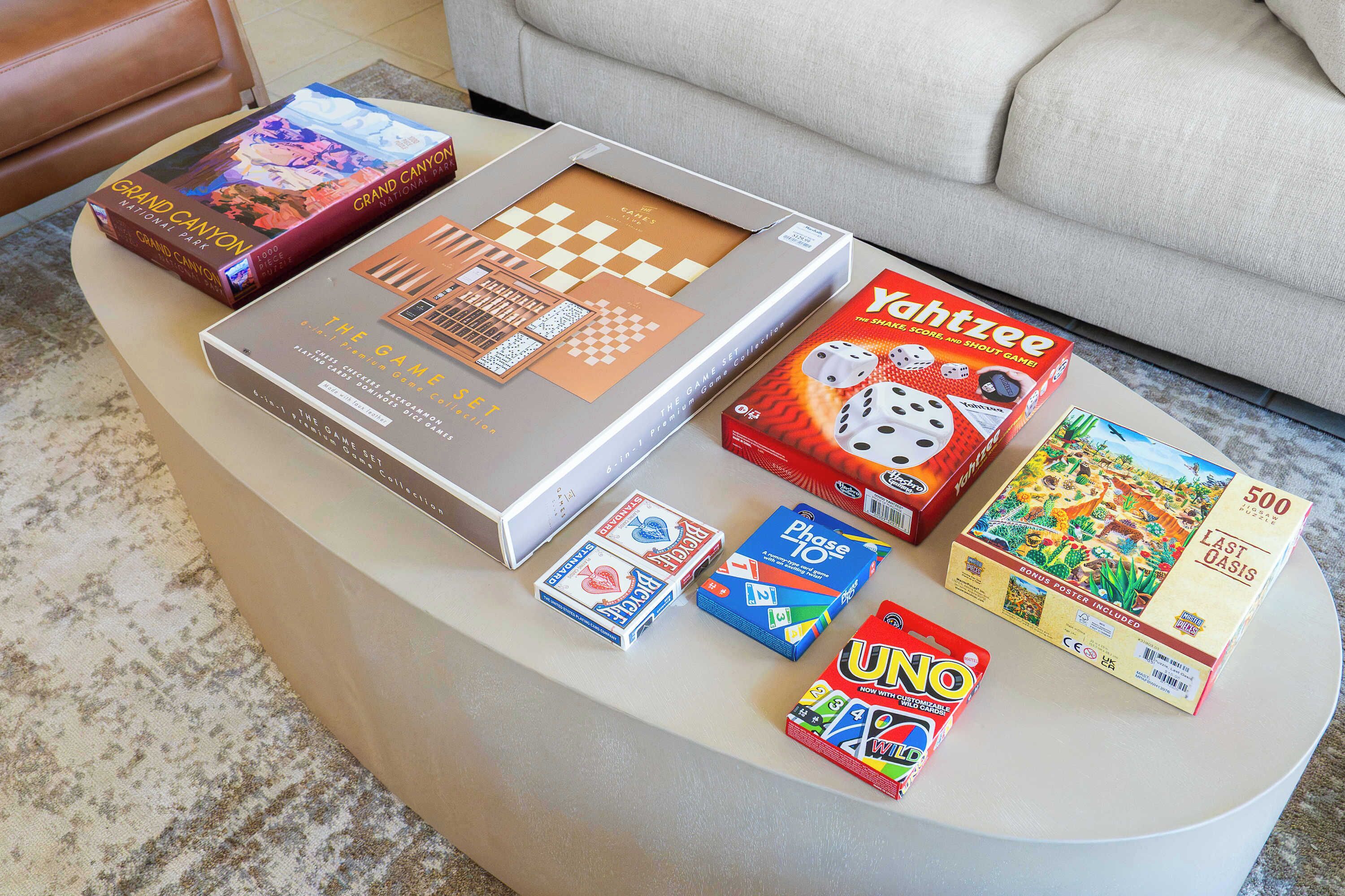 Une table avec divers jeux de société et livres, notamment « Grand Canyon », « Le Jeu de la vie », « Yachtzee », « UNO » et « 500 Last Oasis ».