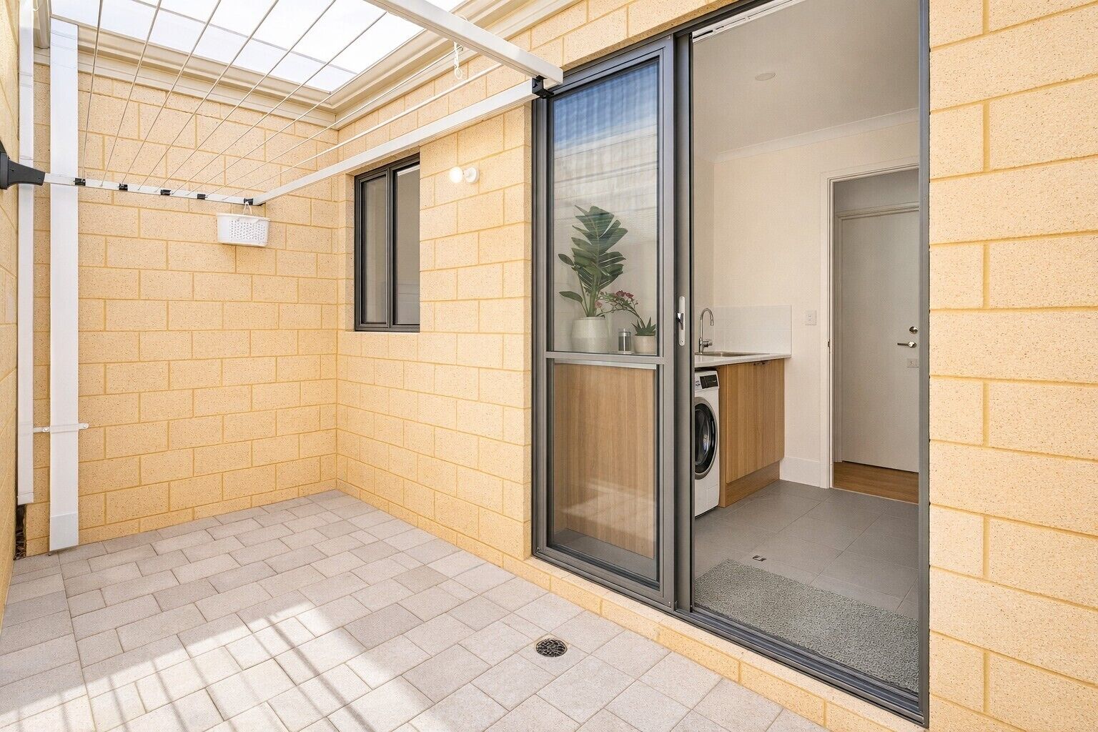 A residential property with a glass door entrance, a small washing machine, and a potted plant.