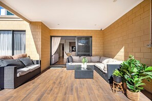 Eine sonnendurchflutete Terrasse mit einer Couch, einem Couchtisch und Topfpflanzen.